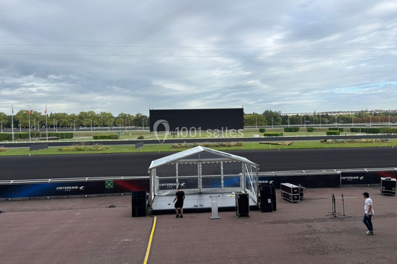 Vue d'une piste de course avec un écran géant éteint en arrière-plan et une structure transparente au premier plan.