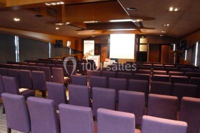 Un groupe de personnes pose sur une scène éclairée, accompagné d'une mascotte en costume d'ours.