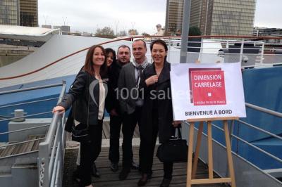 Un groupe de personnes pose sur une scène éclairée, accompagné d'une mascotte en costume d'ours.