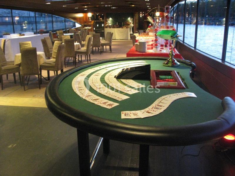 Table de jeu de casino avec cartes étalées, située dans une salle élégante avec vue sur l'eau.