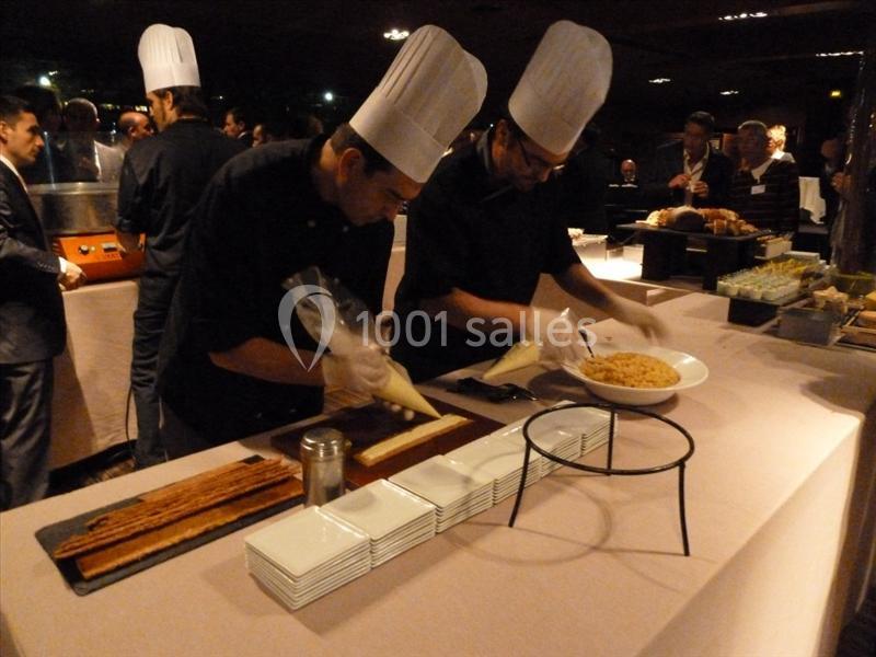 Deux chefs en tenue blanche préparent des plats avec des poches à douille lors d'un événement culinaire.