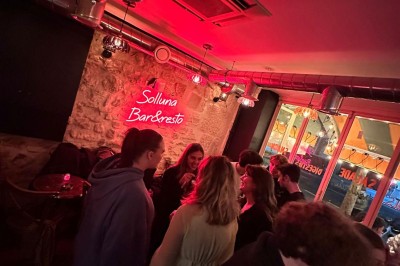 Salle de restaurant chaleureuse avec banquettes rouges, tables en bois sombre et éclairage tamisé par des bougies.