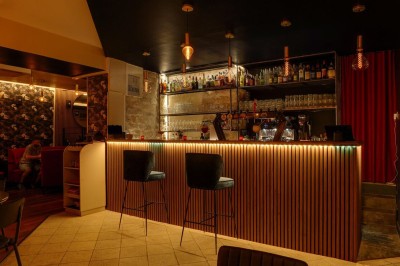 Salle de restaurant chaleureuse avec banquettes rouges, tables en bois sombre et éclairage tamisé par des bougies.