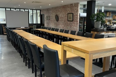 Salle de réunion avec une table dressée contenant des boissons, fruits, viennoiseries et matériel de présentation.