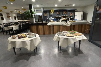 Salle de réunion avec une table dressée contenant des boissons, fruits, viennoiseries et matériel de présentation.