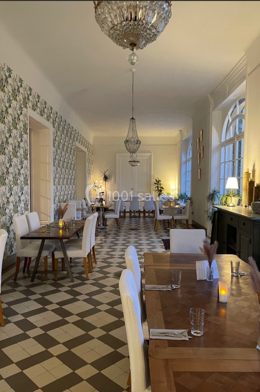 Salle de restaurant lumineuse avec tables en bois, chaises blanches, sol en carreaux et décoration élégante.
