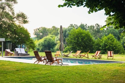 Salle de restaurant lumineuse avec tables en bois, chaises blanches, sol à carreaux et décoration élégante.