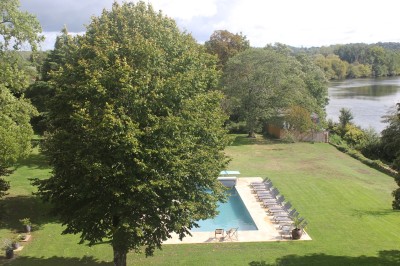 Salle de restaurant lumineuse avec tables en bois, chaises blanches, sol à carreaux et décoration élégante.