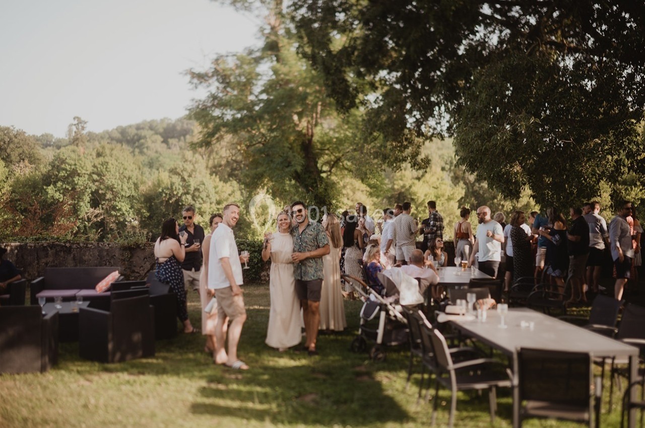 Groupe de personnes réunies en extérieur, discutant et profitant d'un cadre verdoyant par une journée ensoleillée.