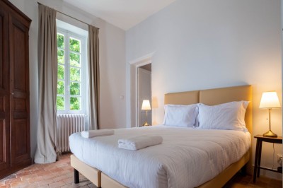 Salle de restaurant lumineuse avec tables en bois, chaises blanches, sol à carreaux et décoration élégante.