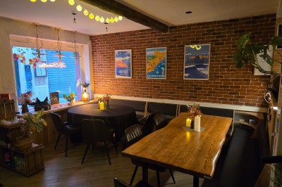 Miniature Location salle Antibes (Alpes-Maritimes) - La Fourmilière #3 Intérieur d'un bar chaleureux avec comptoir en bois, étagères à bouteilles, éclairage tamisé et décorations florales.