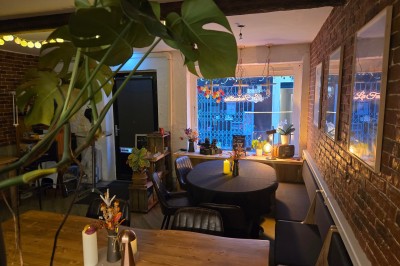 Miniature Location salle Antibes (Alpes-Maritimes) - La Fourmilière #9 Intérieur d'un bar chaleureux avec comptoir en bois, étagères à bouteilles, éclairage tamisé et décorations florales.