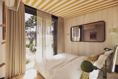 Vue aérienne d'une petite maison avec terrasse en bois, salon, chambre, salle de bain et environnement naturel autour.