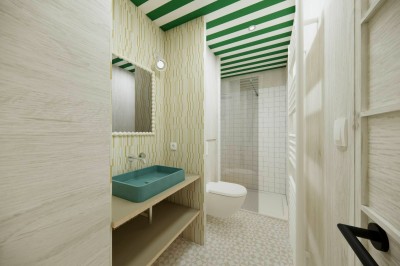 Vue aérienne d'une petite maison avec terrasse en bois, salon, chambre, salle de bain et environnement naturel autour.