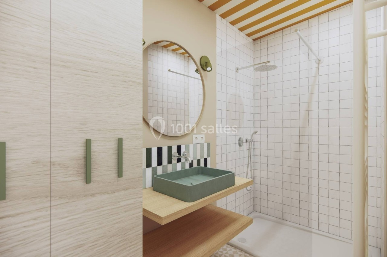 Salle de bain moderne avec douche, lavabo vert sur étagère en bois, miroir rond et carrelage blanc.