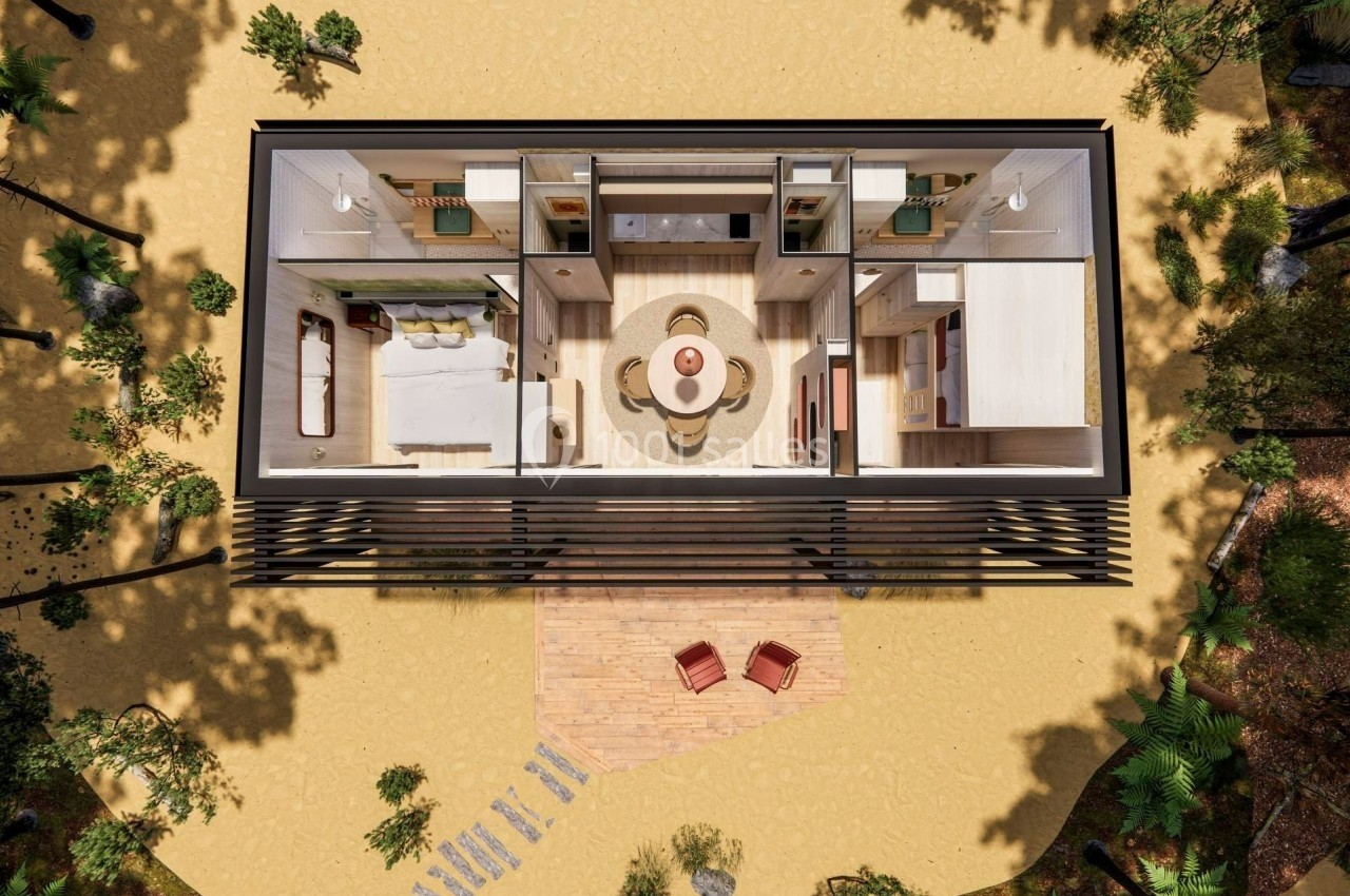 Vue aérienne d'une maison modulaire avec intérieur aménagé, entourée de sable et de végétation.