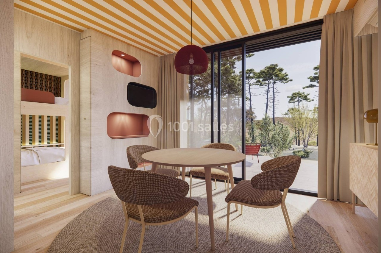 Salle à manger lumineuse avec table ronde, chaises en rotin, lits superposés intégrés et vue sur un jardin arboré.