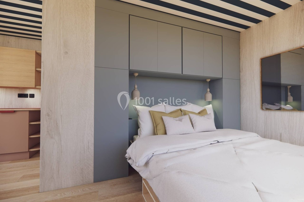 Lit double avec draps blancs, encadré par des rangements intégrés gris, dans une chambre au design moderne et épuré.