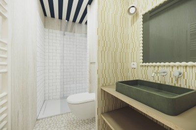 Vue aérienne d'une petite maison avec terrasse en bois, salon, chambre, salle de bain et environnement naturel autour.