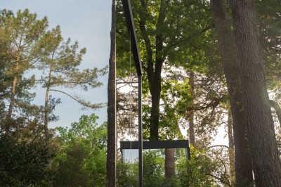 Miniature Hébergement - MIROIR Terrain de padel clôturé entouré de végétation et d'arbres, avec un chemin en bois adjacent.
