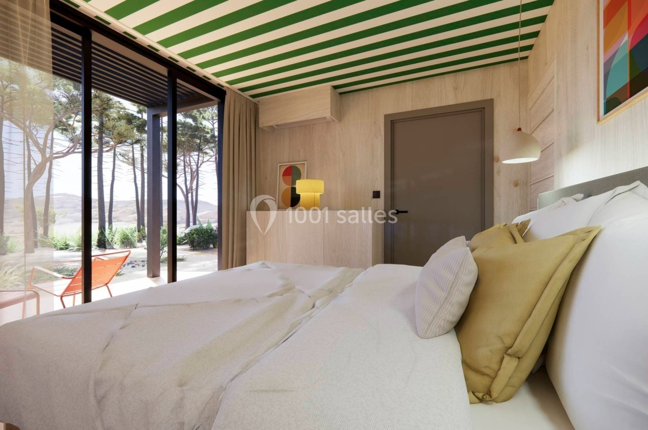 Chambre lumineuse avec lit double, grande baie vitrée donnant sur un jardin et plafond à rayures vertes et blanches.