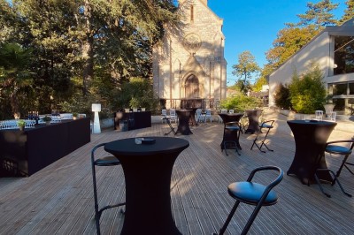 Allée bordée de grands arbres et de feuilles tombées, longeant une balustrade en pierre au coucher du soleil.