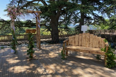Allée bordée de grands arbres et de feuilles tombées, longeant une balustrade en pierre au coucher du soleil.
