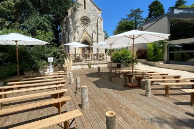 Allée bordée de grands arbres et de feuilles tombées, longeant une balustrade en pierre au coucher du soleil.