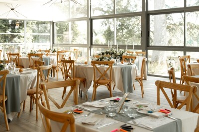 Allée bordée de grands arbres et de feuilles tombées, longeant une balustrade en pierre au coucher du soleil.