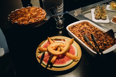 Chambre d'hôtel moderne avec lit double, décor en bois, salle de bain ouverte et vue sur l'extérieur par une baie vitrée.
