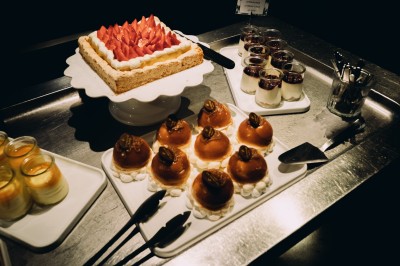 Chambre d'hôtel moderne avec lit double, décor en bois, salle de bain ouverte et vue sur l'extérieur par une baie vitrée.