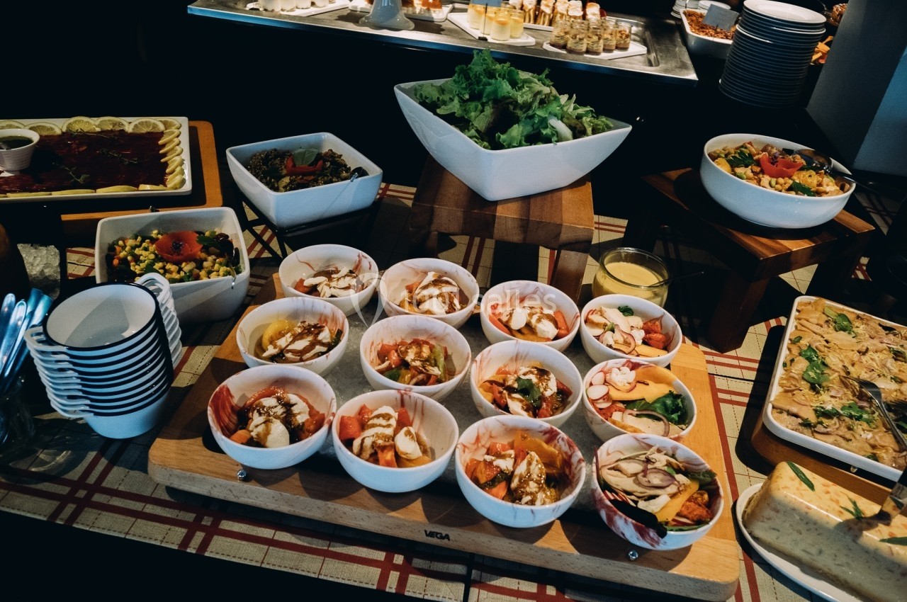 Buffet varié avec salades, légumes, plats préparés et assiettes disposés sur une table.