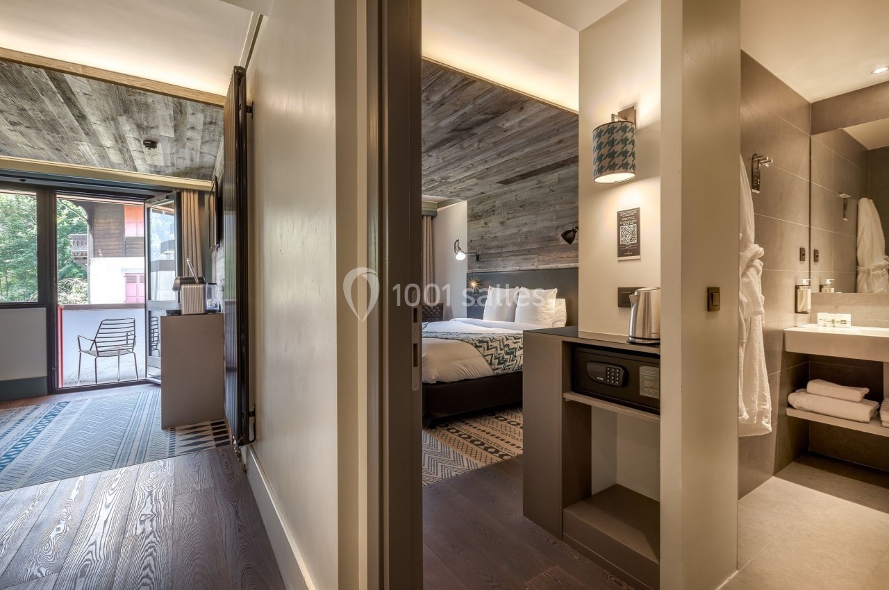 Vue d'une chambre d'hôtel moderne avec salle de bain attenante, balcon et décoration en bois.