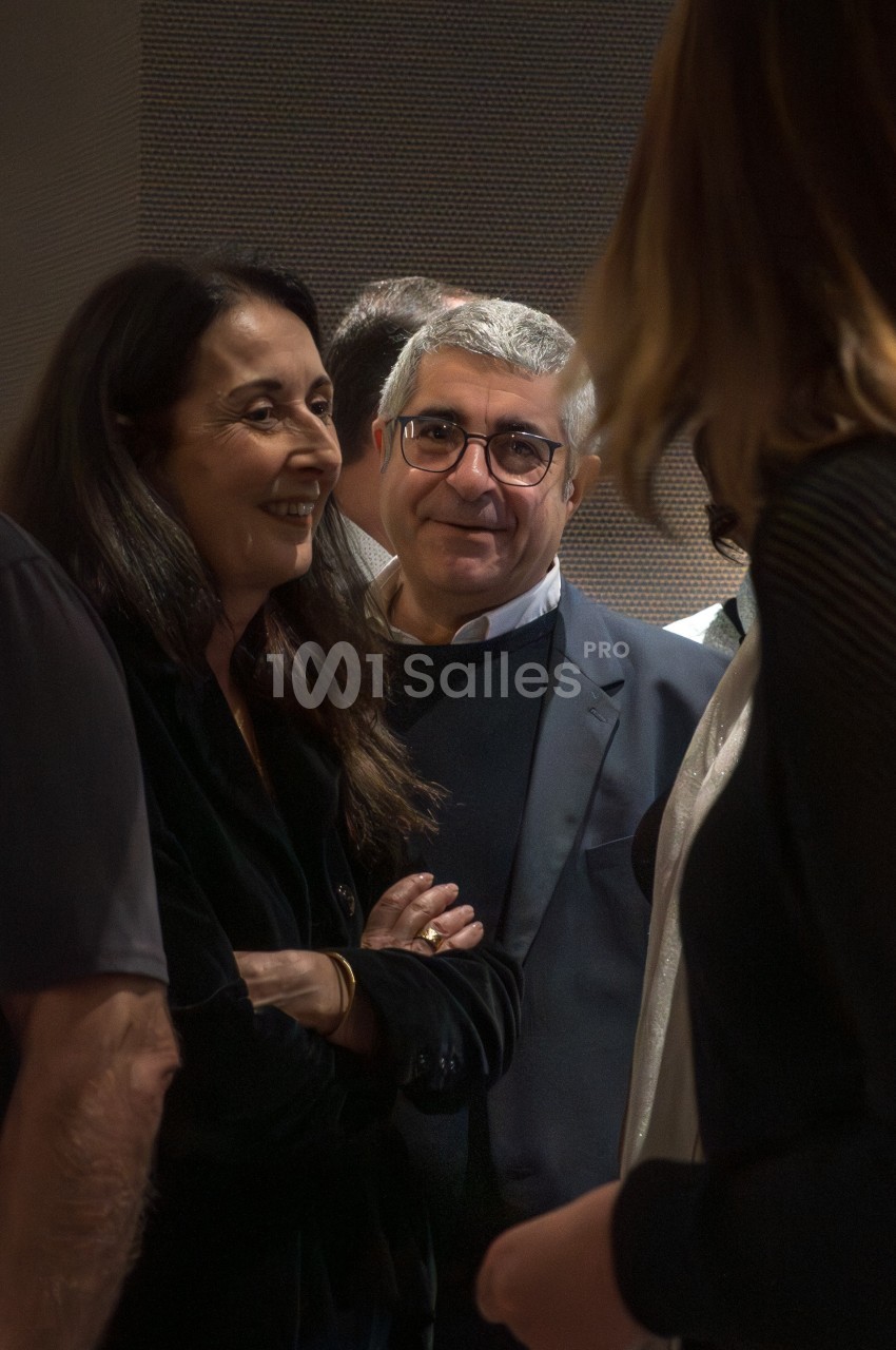 Deux personnes discutent dans un groupe lors d'un événement, l'une souriante et l'autre regardant vers l'objectif.