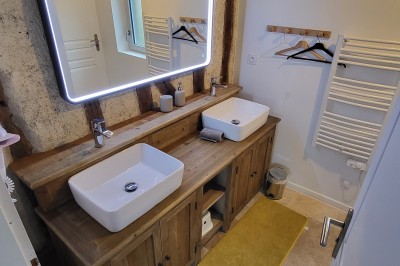 Bâtiment en pierre éclairé par des lumières extérieures, dans une cour sombre au crépuscule.