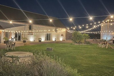 Bâtiment en pierre éclairé par des lumières extérieures, dans une cour sombre au crépuscule.