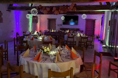 Bâtiment en pierre éclairé par des lumières extérieures, dans une cour sombre au crépuscule.