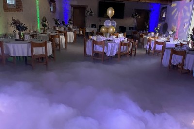 Bâtiment en pierre éclairé par des lumières extérieures, dans une cour sombre au crépuscule.