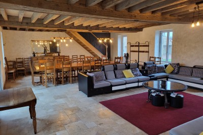 Bâtiment en pierre éclairé par des lumières extérieures, dans une cour sombre au crépuscule.