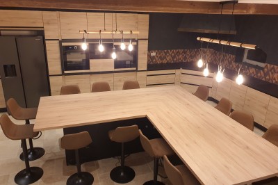 Bâtiment en pierre éclairé par des lumières extérieures, dans une cour sombre au crépuscule.