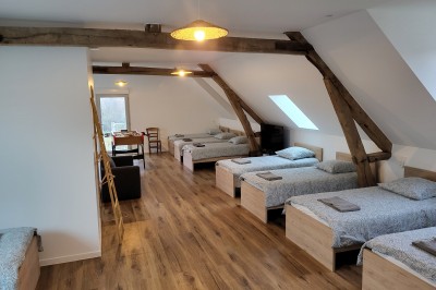 Bâtiment en pierre éclairé par des lumières extérieures, dans une cour sombre au crépuscule.