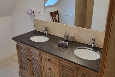 Bâtiment en pierre éclairé par des lumières extérieures, dans une cour sombre au crépuscule.