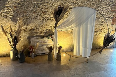 Bâtiment en pierre éclairé par des lumières extérieures, dans une cour sombre au crépuscule.