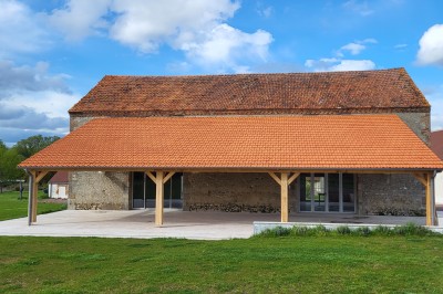 Bâtiment en pierre éclairé par des lumières extérieures, dans une cour sombre au crépuscule.