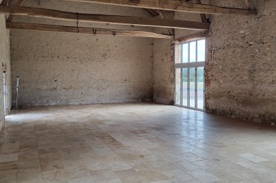 Bâtiment en pierre éclairé par des lumières extérieures, dans une cour sombre au crépuscule.