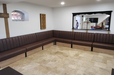 Bâtiment en pierre éclairé par des lumières extérieures, dans une cour sombre au crépuscule.