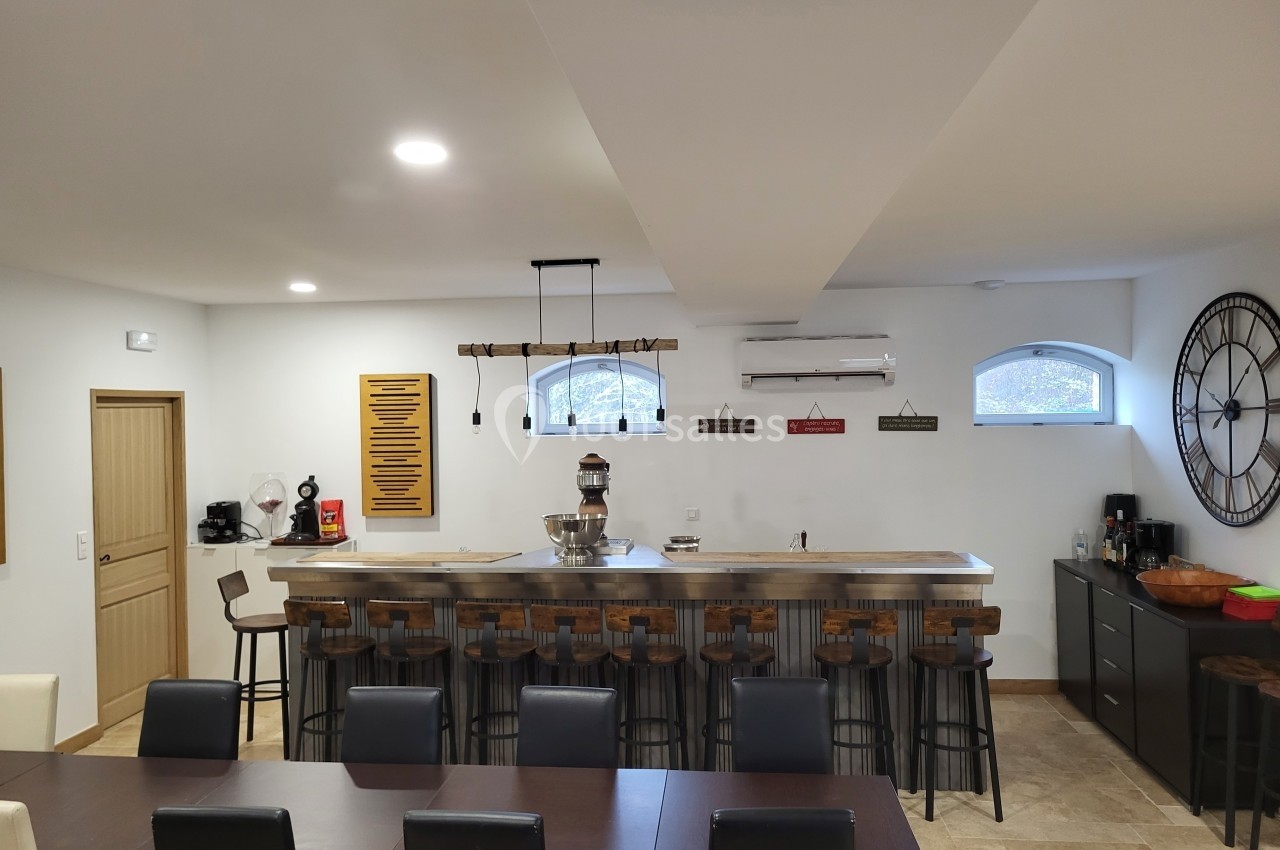 Cuisine spacieuse avec un grand bar en bois, tabourets hauts, table à manger et décorations murales.