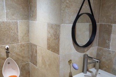 Bâtiment en pierre éclairé par des lumières extérieures, dans une cour sombre au crépuscule.