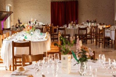 Bâtiment en pierre éclairé par des lumières extérieures, dans une cour sombre au crépuscule.