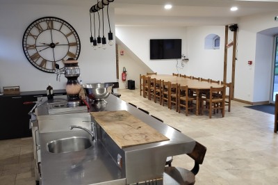 Bâtiment en pierre éclairé par des lumières extérieures, dans une cour sombre au crépuscule.